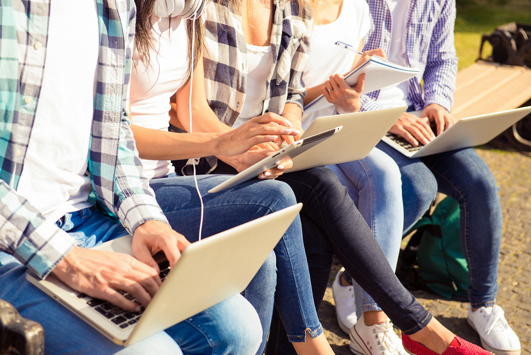stock-photo-close-up-photo-of-happy-diverse-classmates-sitting-on-bench-and-study-up-with-device-524899705
