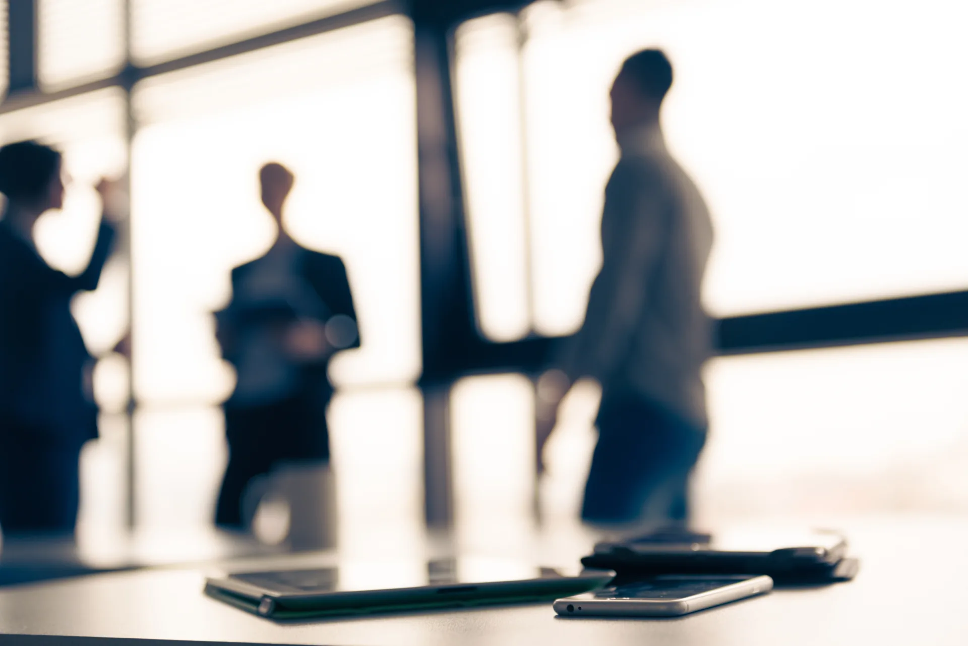 close up of tablet, business people on meeting in background