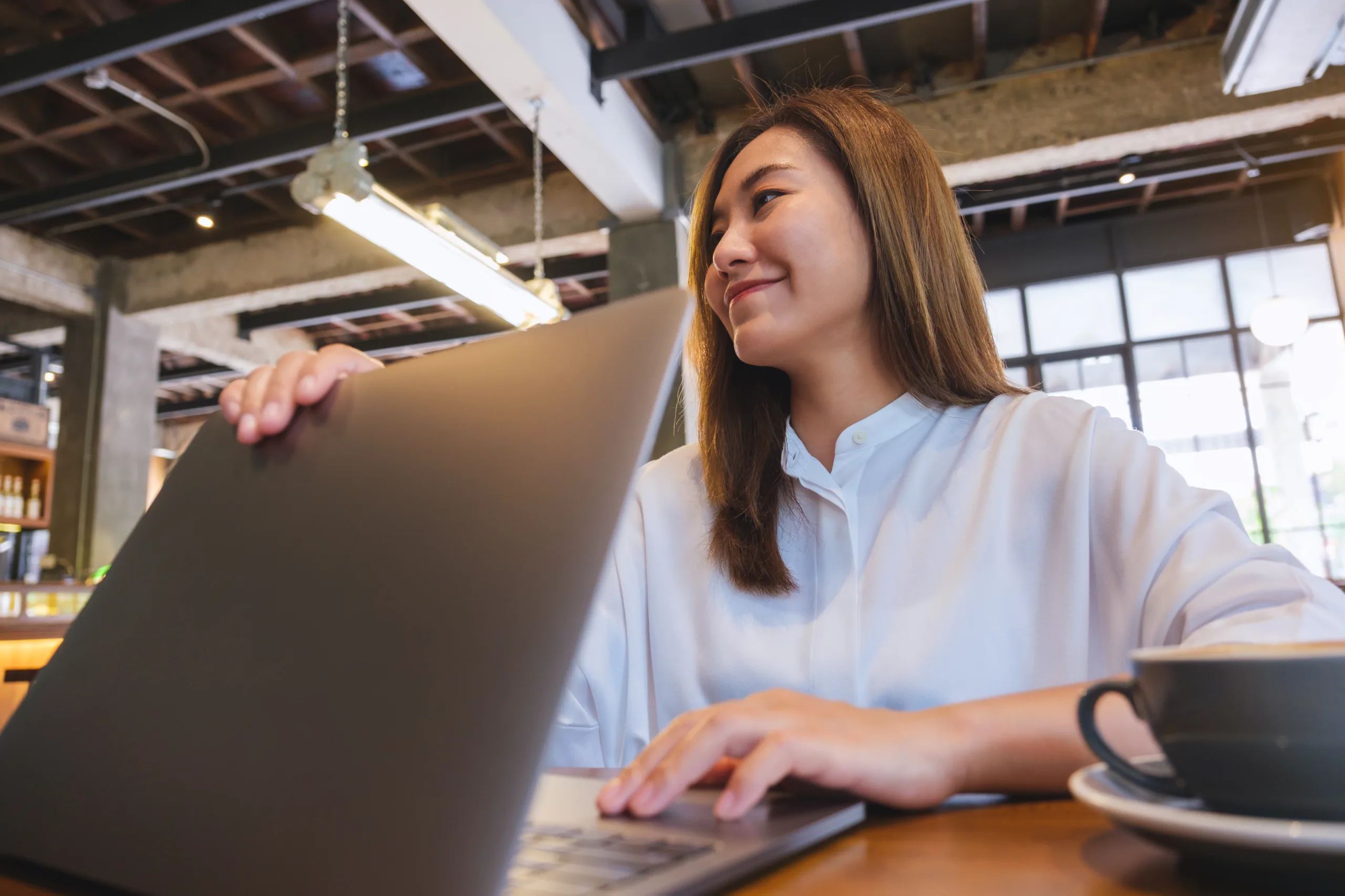 a young woman opening or closing laptop computer, getting ready for work, finished work in office